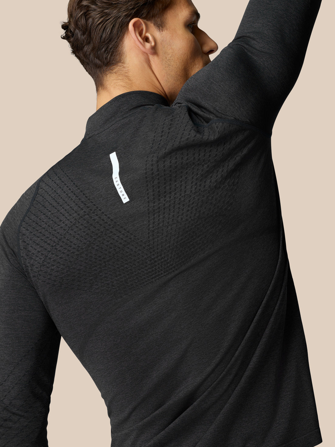 Back view of Flow Training Top in black with knitted back panels and a white label at the shoulder.