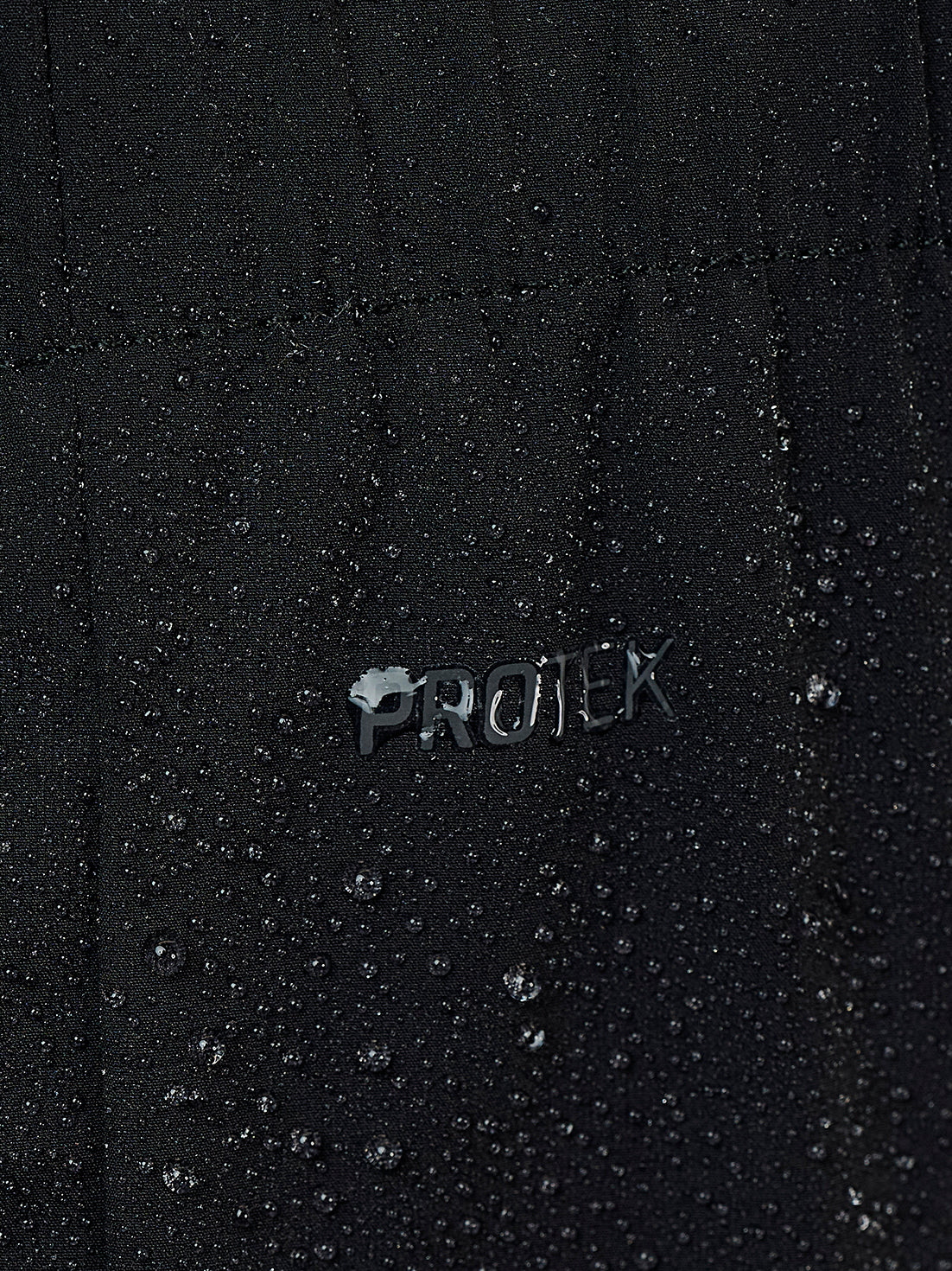 Close-up of a black waterproof fabric covered in water droplets, with a metallic 'PROTEK' logo in the center showing water beading on top.