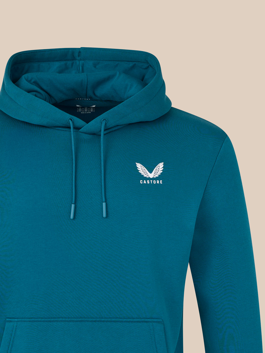 Teal hoodie with a logo on the chest against a beige background
