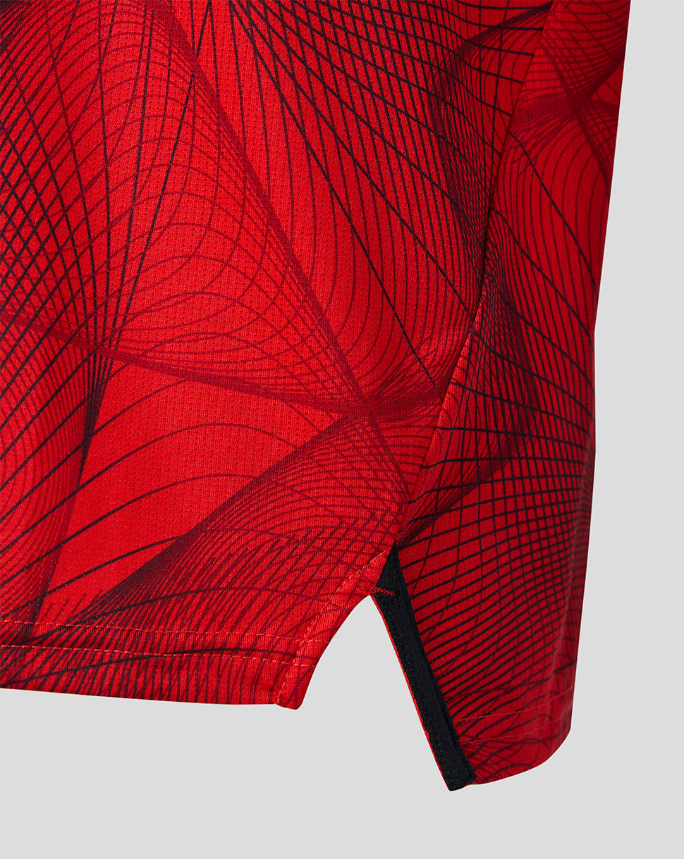 Close up of the red Feyenoord Junior home shirt showing the black abstract pattern and sleeve hem detail.