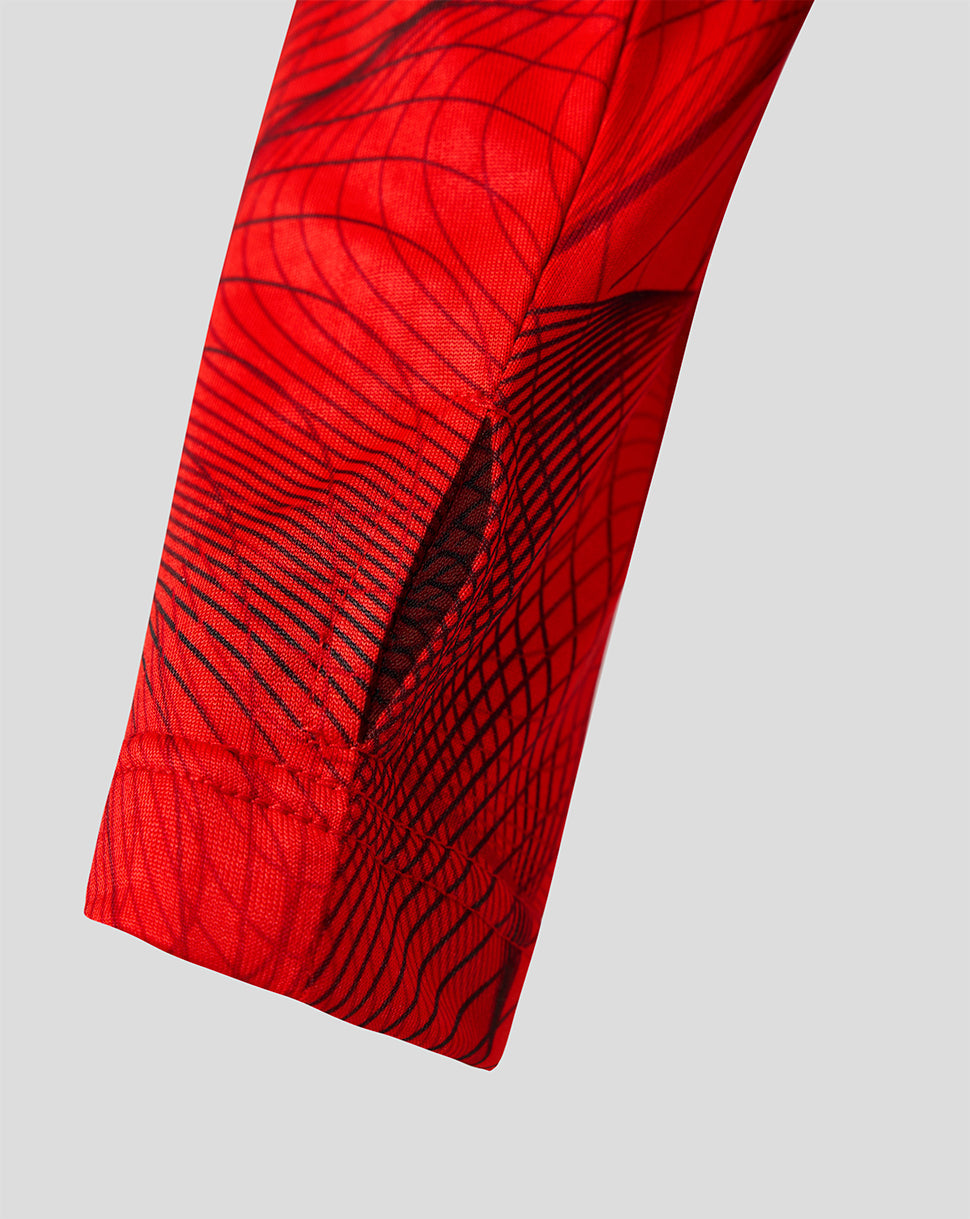 Close up of red Feyenoord Junior 2026-27 home midlayer sleeve with black abstract lines.