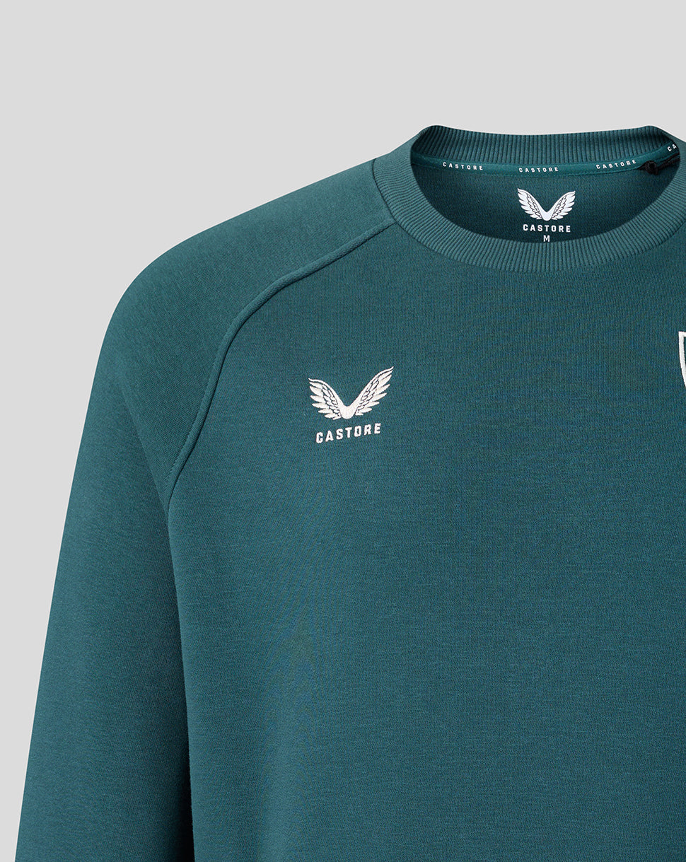 Close-up of teal sweatshirt neckline and shoulder with Castore label inside neck and chest crest.