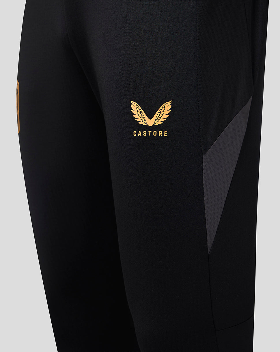 Close up of black training pants with gold Castore logo and gray panel on the thigh