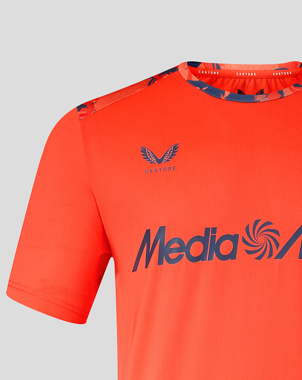 Close-up of bright orange Feyenoord shirt showing crest on the chest and Castore logo on the opposite side with a patterned collar trim.
