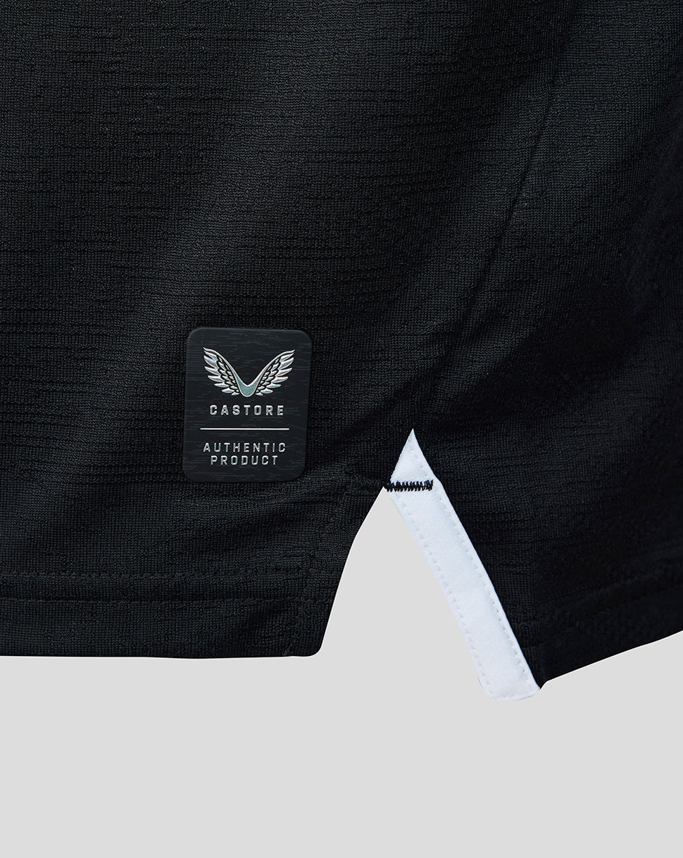 Close-up of the lower side of a black athletic shirt with Castore authentic product badge and white trim