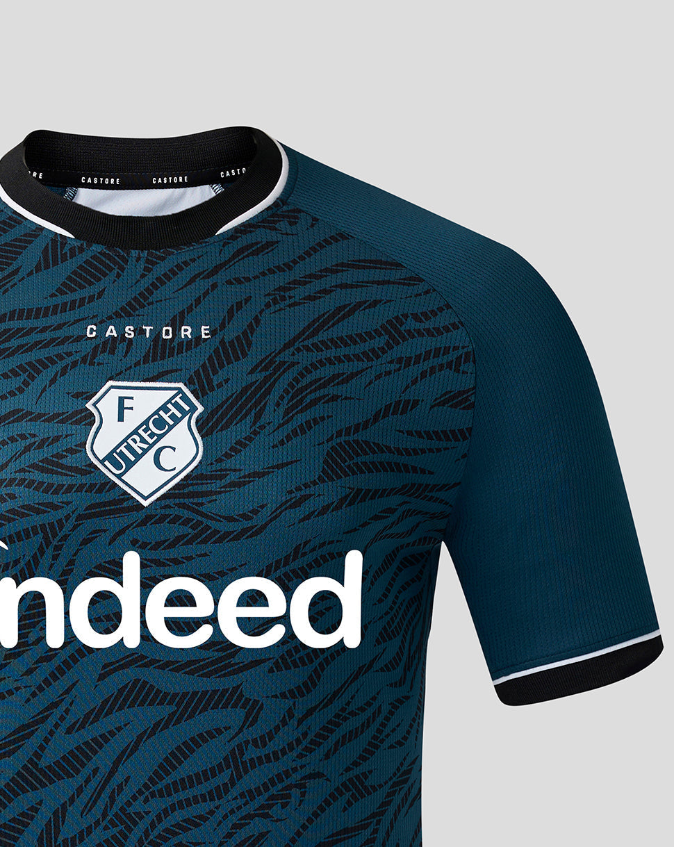 Close-up of chest on teal FC Utrecht away shirt showing the Indeed sponsor logo, Castore branding, and shield crest.