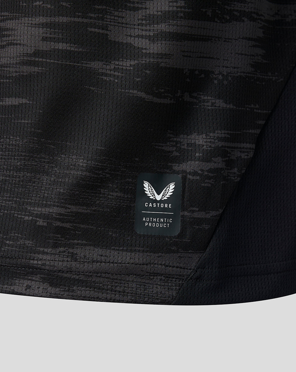 Detail of the lower hem showing Castore authentic product patch on dark camo fabric