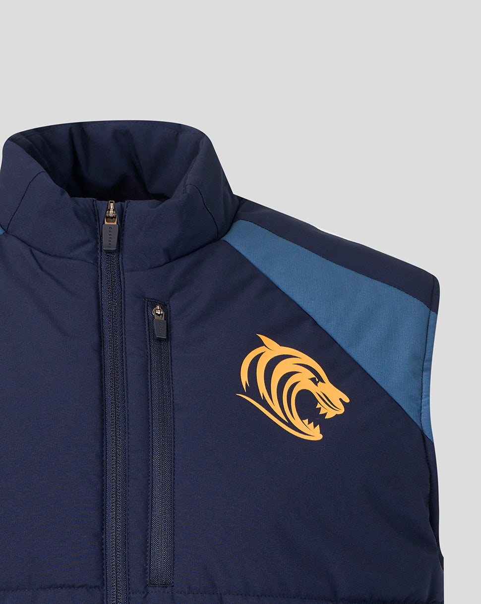Close-up of a navy blue puffer vest with a light blue shoulder panel and a yellow tiger head logo on the chest, shown against a light gray background.