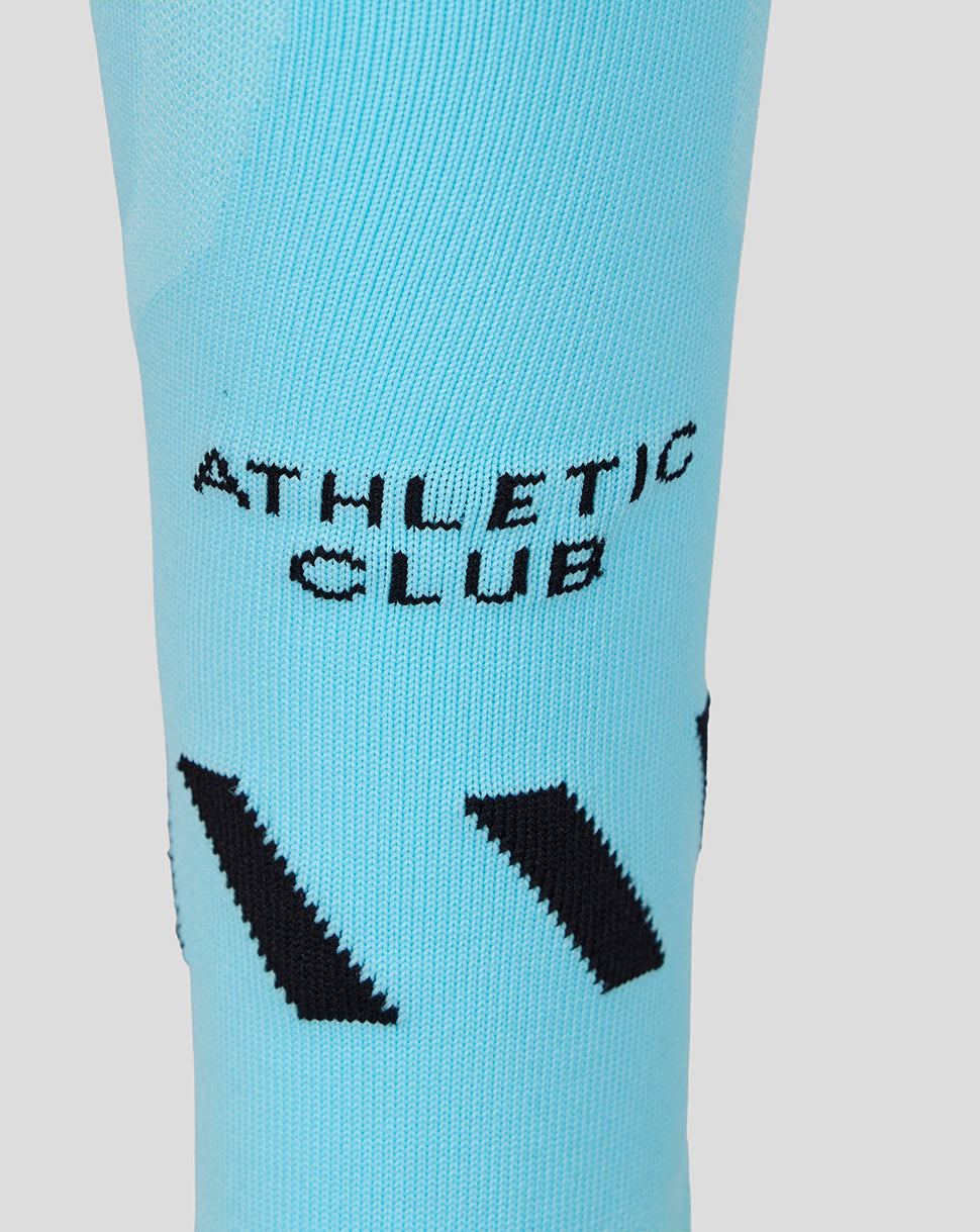 Full-length turquoise sock with light blue and gray accents and black chevrons from the Athletic Club Junior 26/27 third kit.