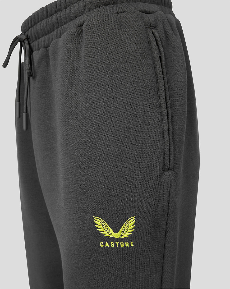 Close-up of dark gray sweatpants with a yellow embroidered wing logo and the brand name 'CASTORE' on the lower left leg, featuring an elastic drawstring waistband.