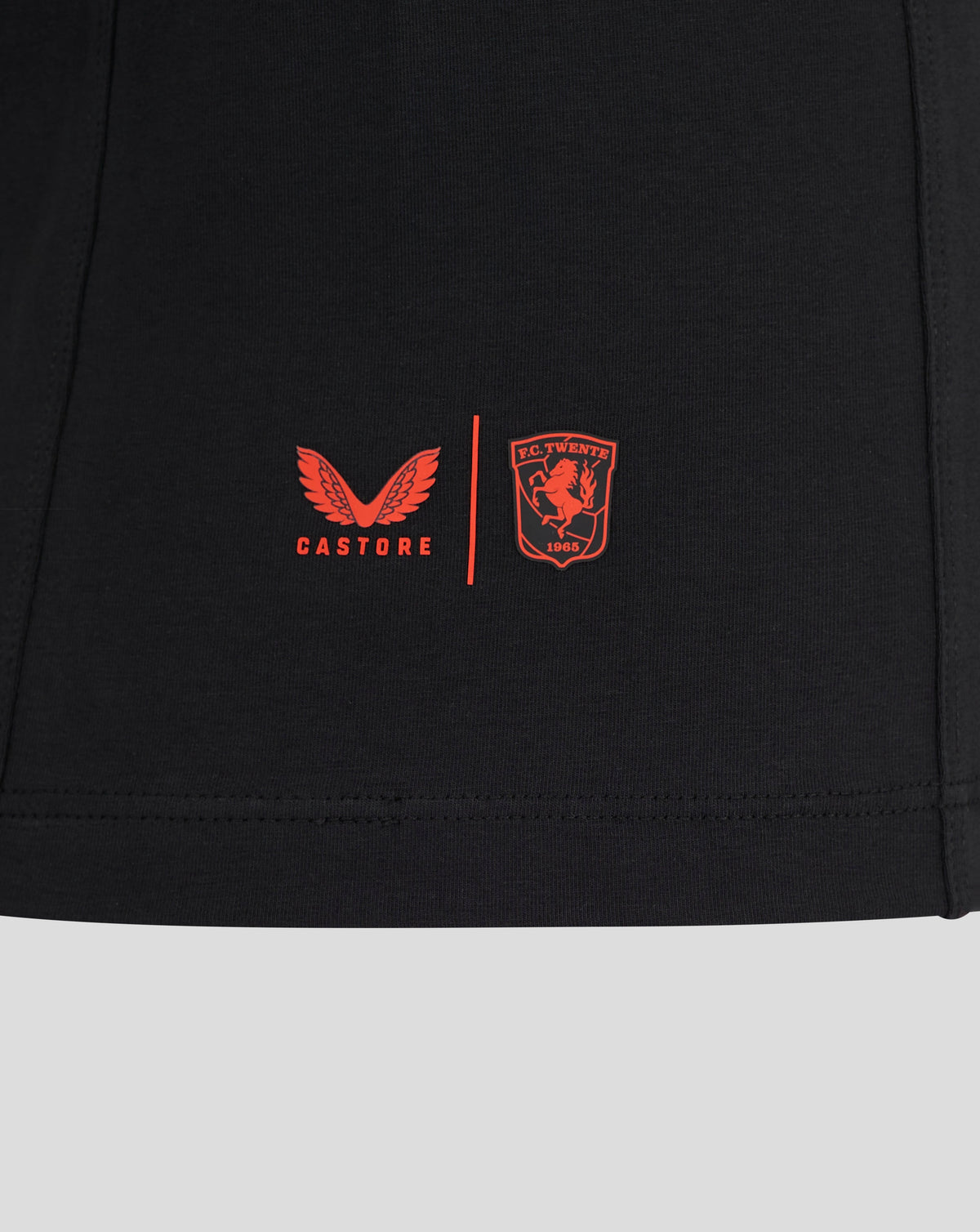 Lower chest close-up on black FC Twente travel T shirt featuring red wing graphic, club crest and Castore branding