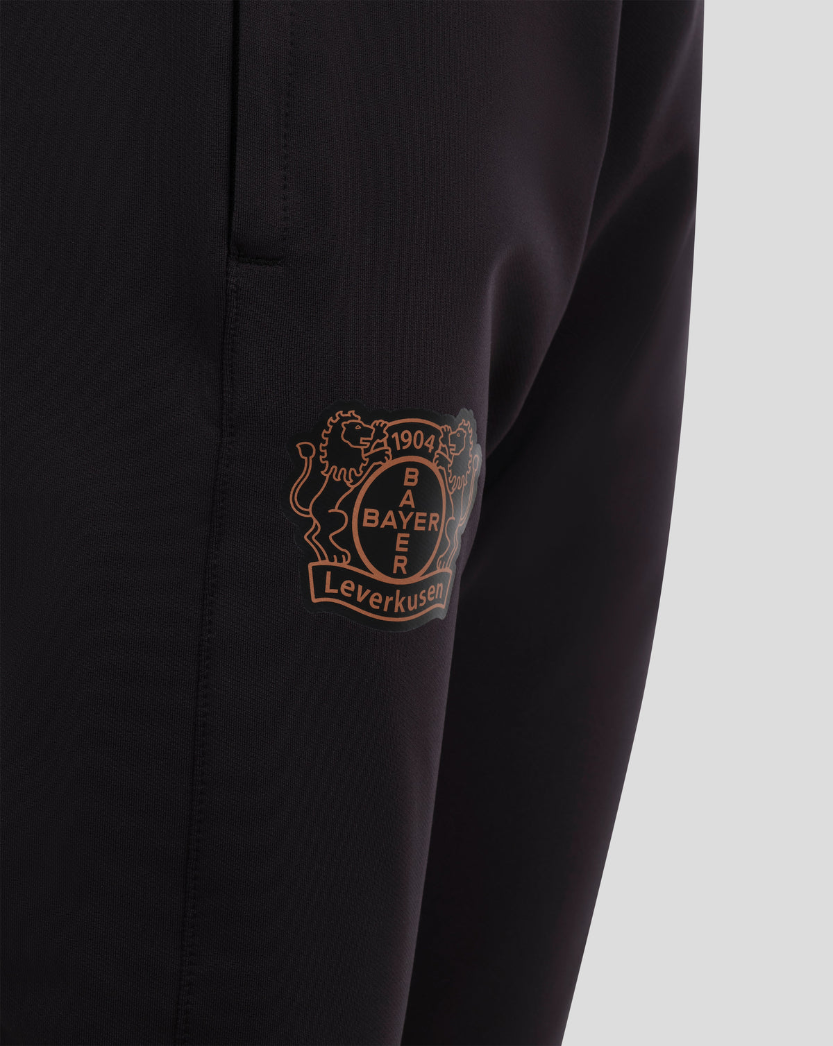 Back view of black Bayer Leverkusen junior training pants with elastic waistband and team crest on the leg