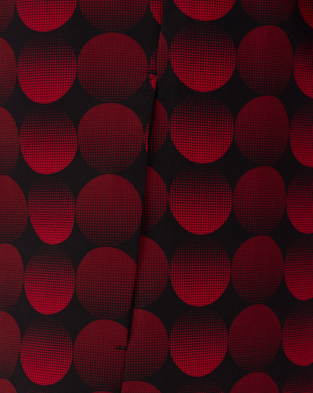 Close-up of red circular dotted pattern on black fabric from the Feyenoord 2025-2026 home matchday jacket, with a center seam visible.