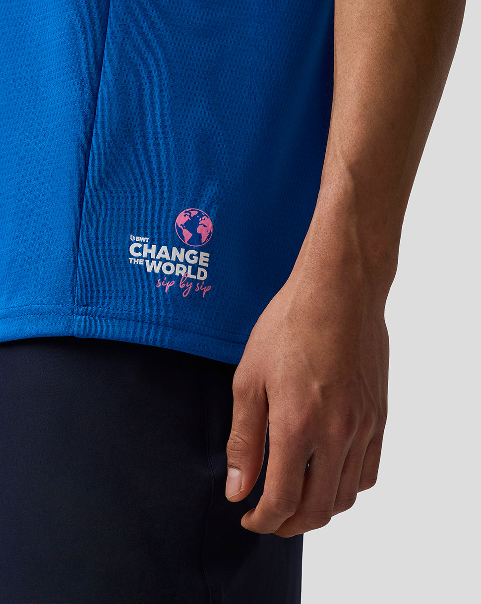 Close-up of blue BWT Alpine shirt with Change the World emblem and pink globe near the hem