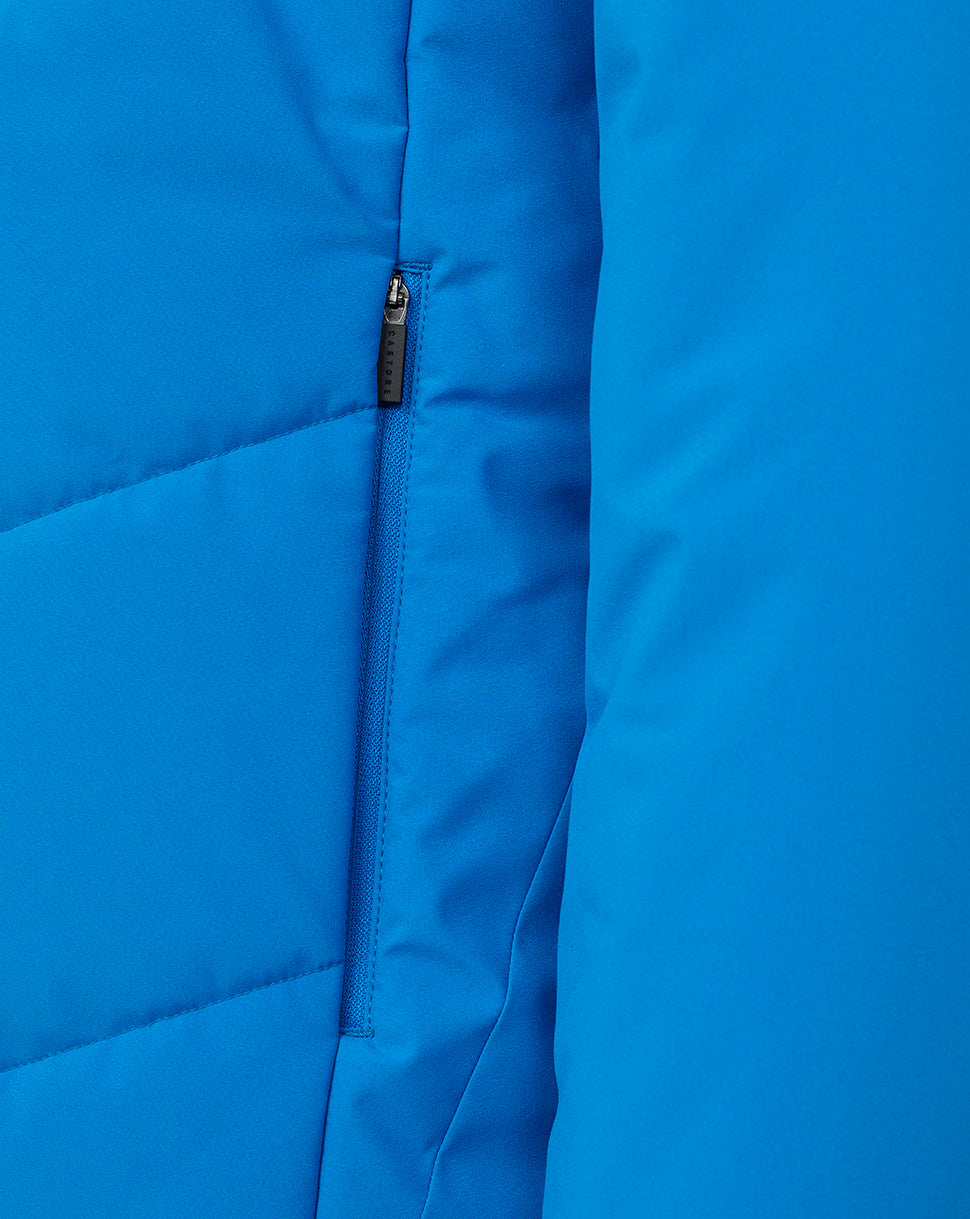 Close up of bright blue padded FC Twente jacket showing a vertical zipper pocket.