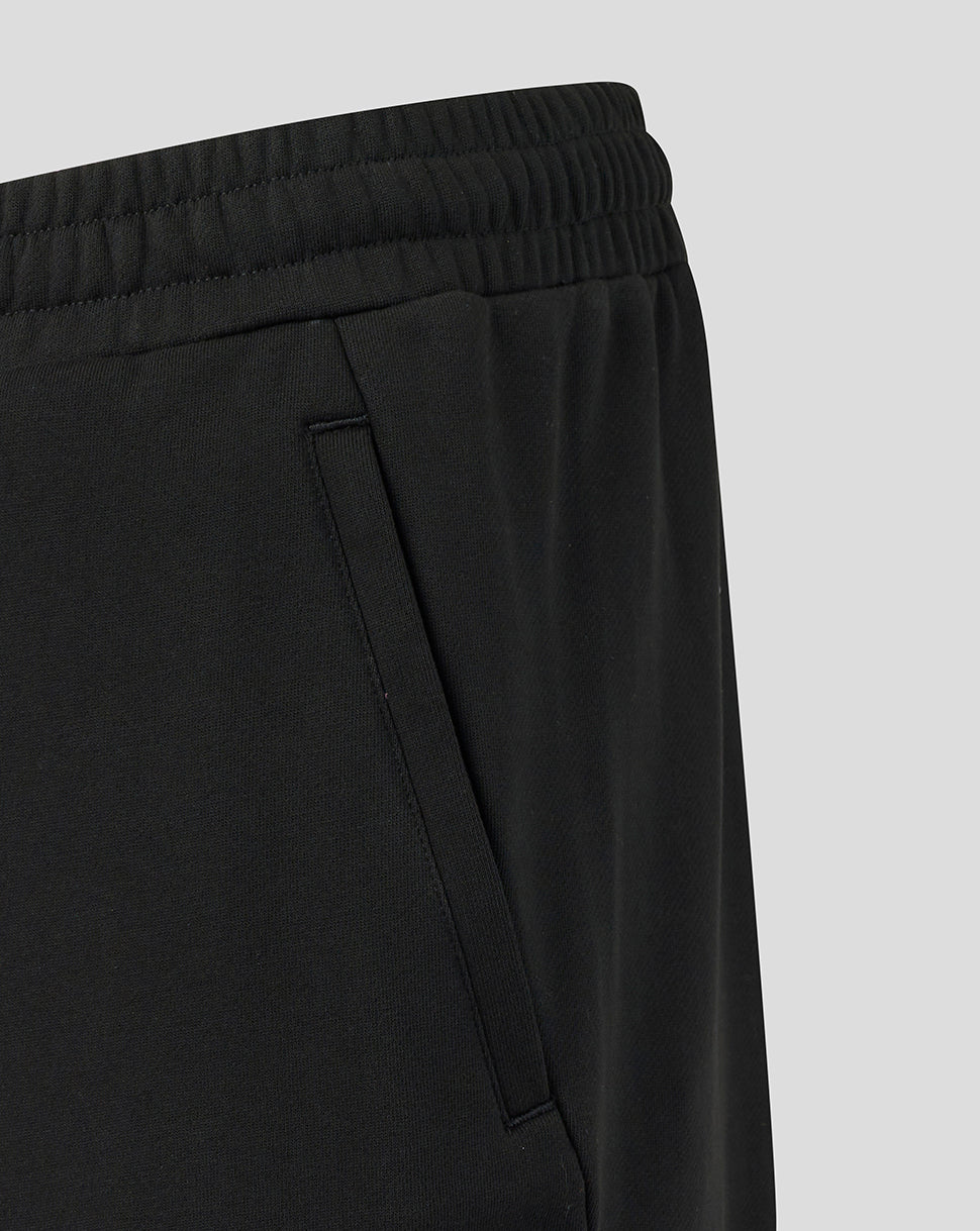 Black pants with a focus on the waistband and side seam against a light gray background