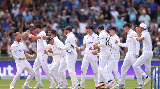 England cricketers in white uniforms celebrate on the field during the Ashes 2023 match.