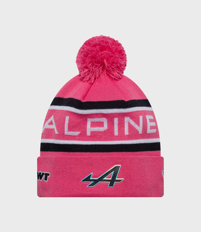 Pink knit beanie with fluffy pompom and Alpine branding on striped cuff