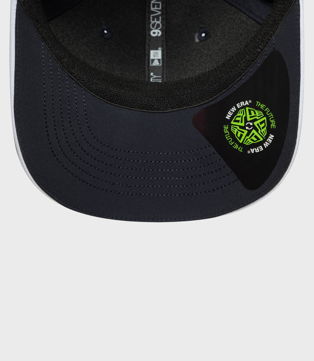 Top view of navy cap brim with neon green circular patch and inner crown label