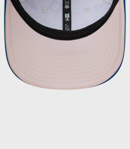 Close-up of pale pink crown with black inner trim and teal brim edge on a curved snap cap
