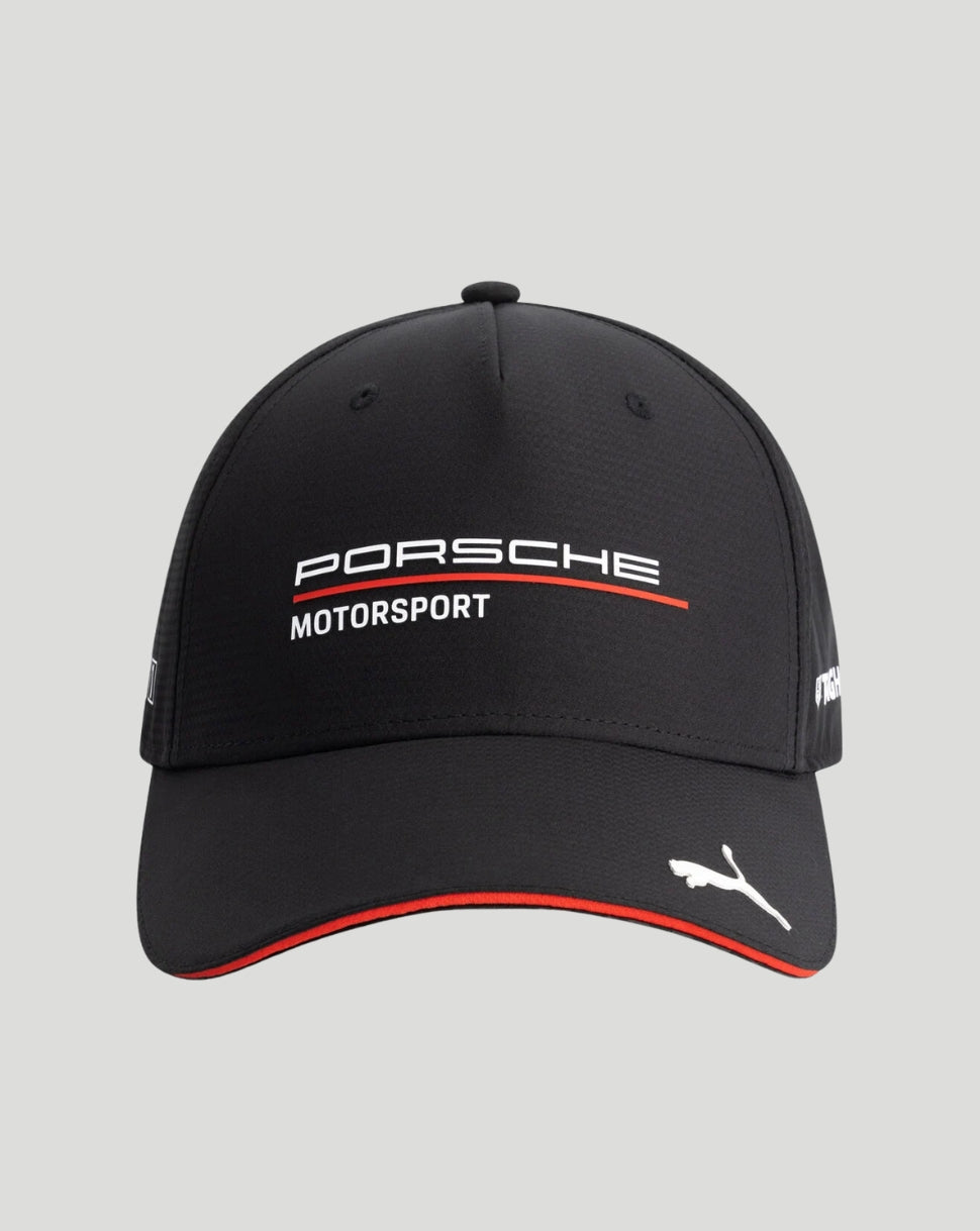 A black Puma Porsche Motorsport baseball cap featuring white embroidered logos and a red accent line on the front and brim, set against a solid light gray background.