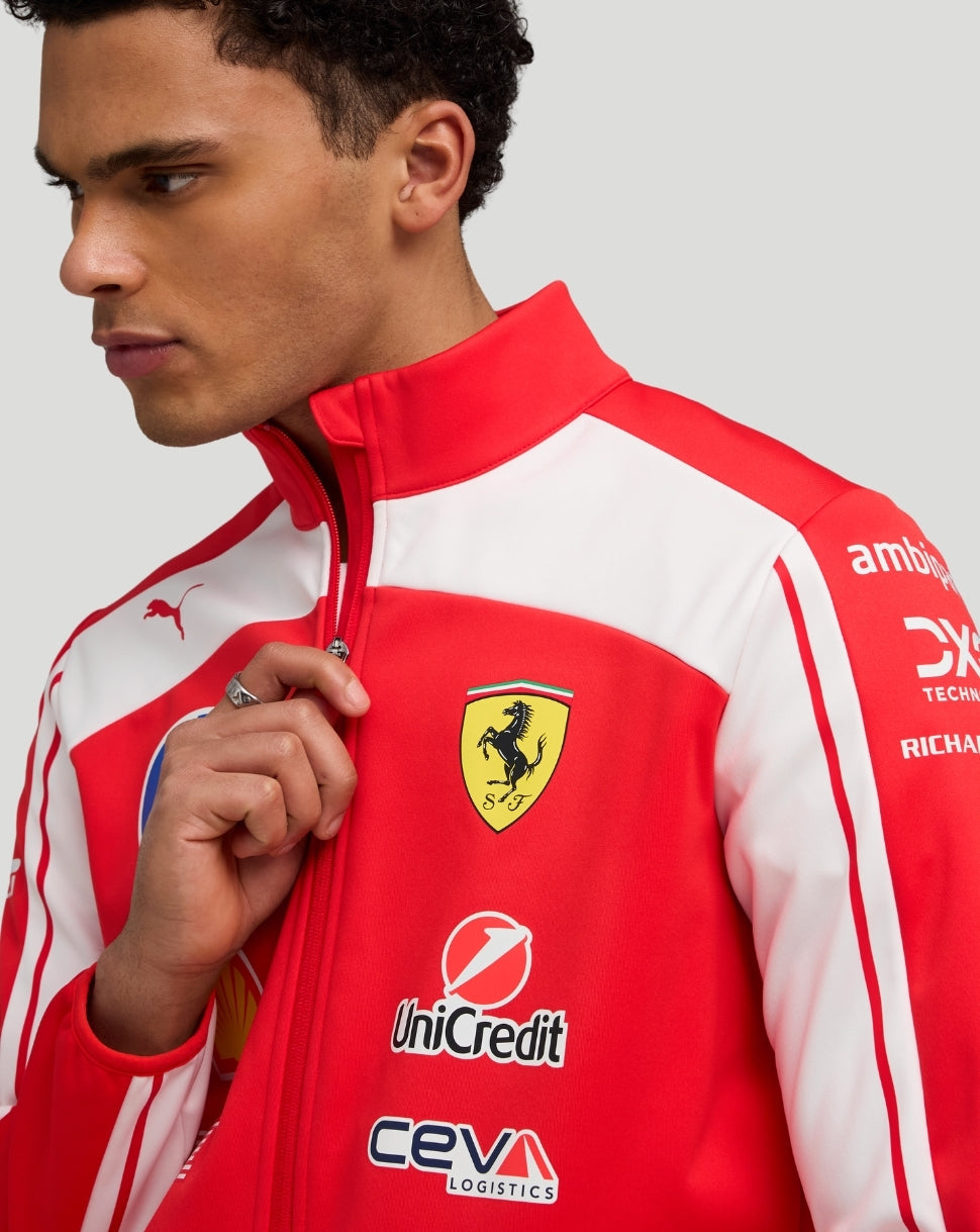 Close-up of a model wearing the red Scuderia Ferrari team jacket, showing the Ferrari crest on the chest, Puma logo, and sponsor branding.