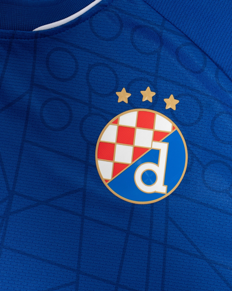 Close-up of the club crest on the blue Dinamo Zagreb junior shirt with three gold stars above.