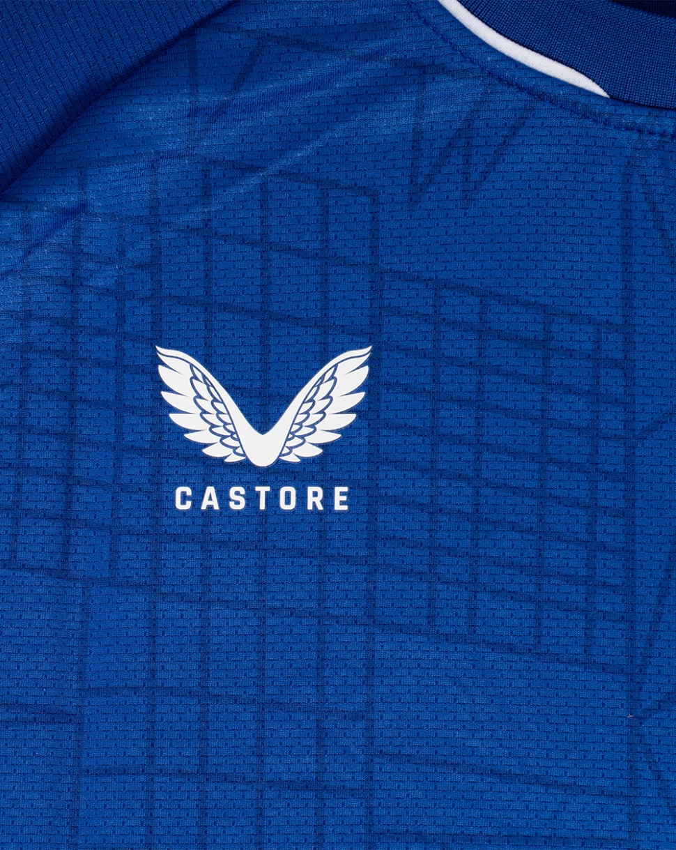 Close-up of CASTORE logo with wing emblem on a textured blue Dinamo Zagreb junior shirt.