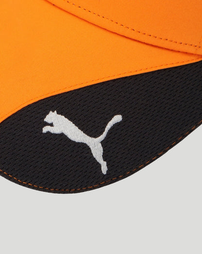 Close up of curved black cap brim with white Puma logo against bright orange cap fabric.