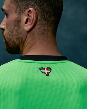 Back view of neon green goalkeeper jersey showing a small flag badge on the upper back.