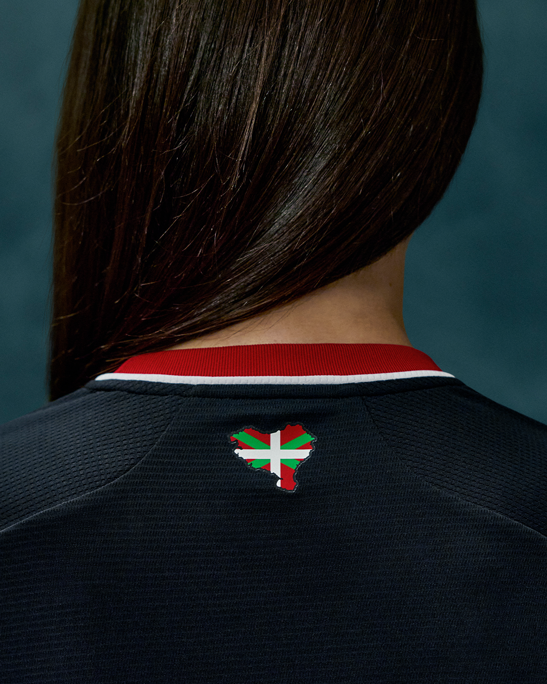 Back view of a woman in the Athletic Club 26/27 away shirt with Basque flag crest visible at the upper back