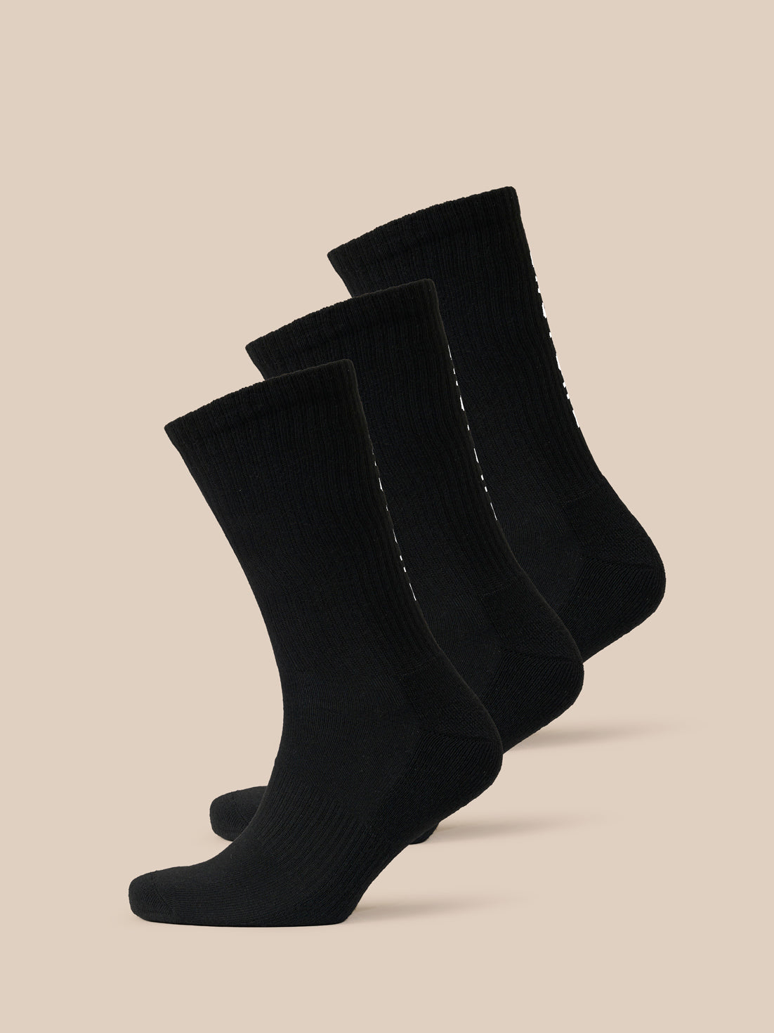 Three black Castore X Ridgeway crew socks arranged diagonally against a beige background