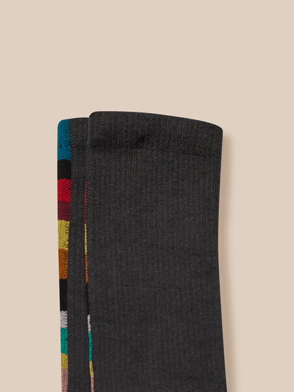 Black sock with colorful striped pattern on a beige background