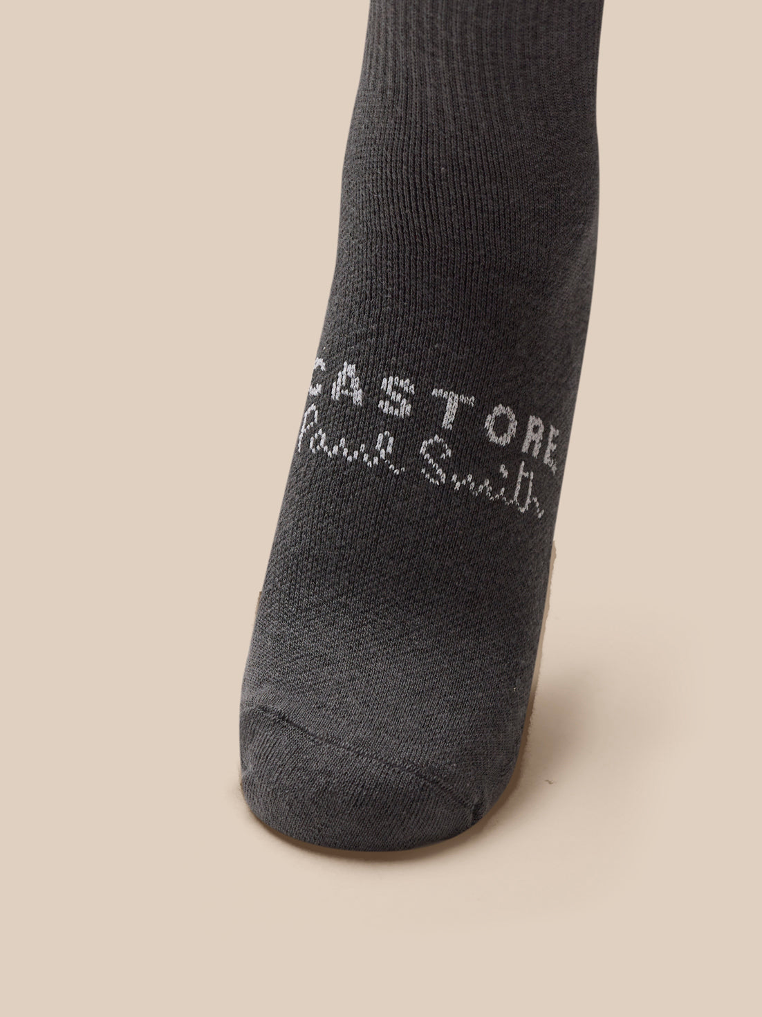Black sock with branding on a beige background