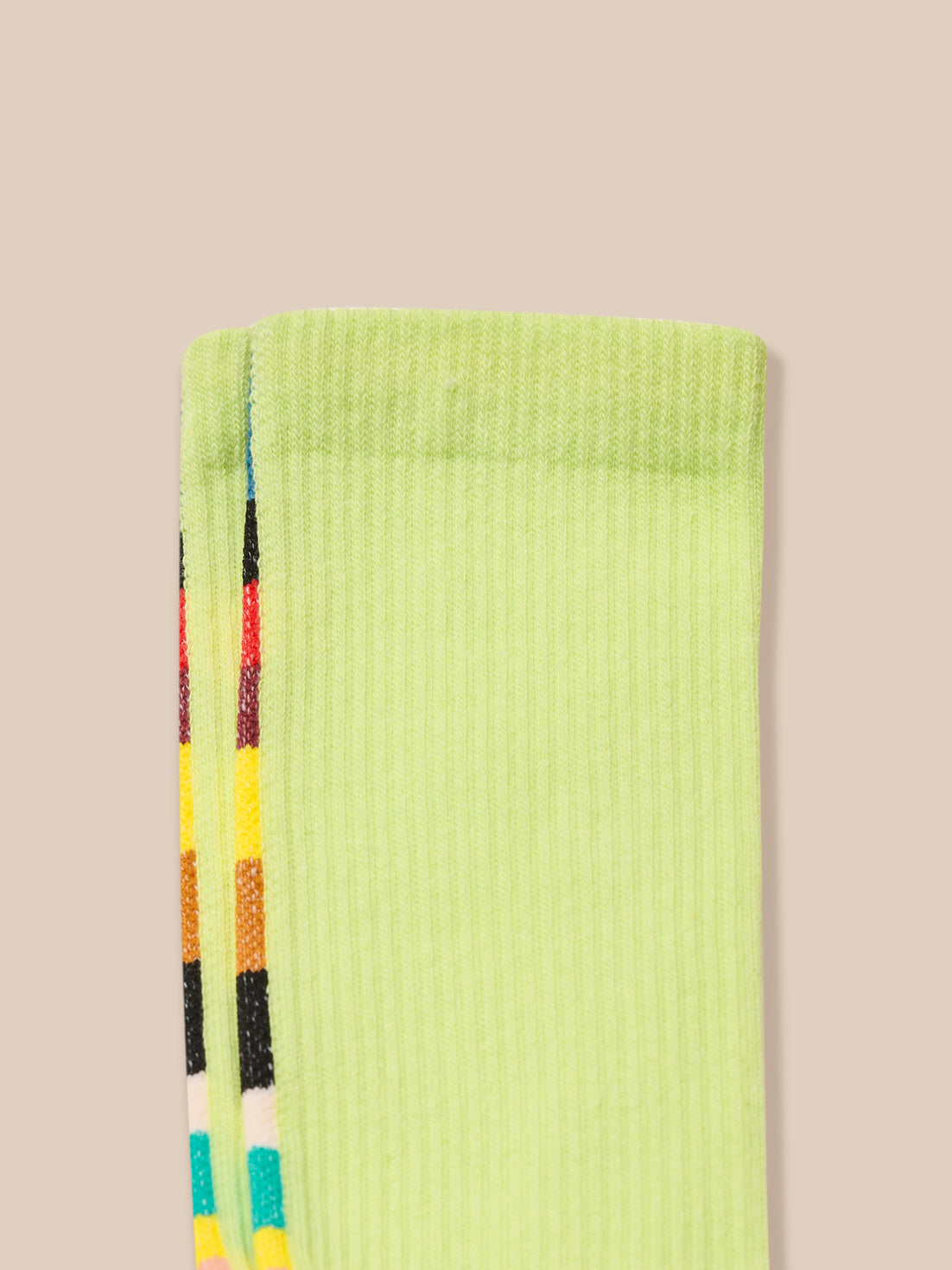 Light green sock with colorful stripes on a beige background