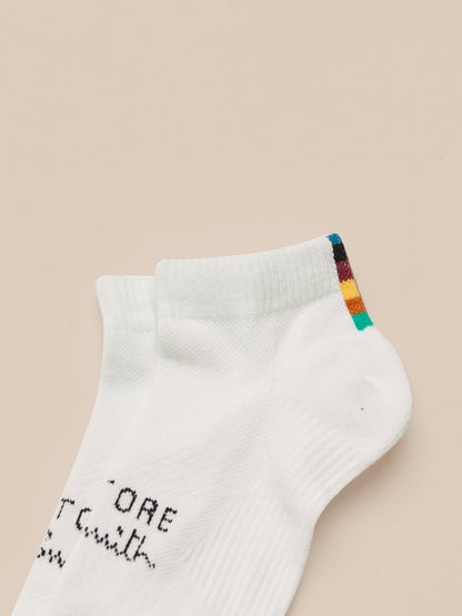 White ankle sock with colorful heel and toe area on a beige background