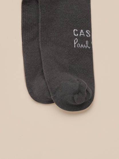 Dark gray socks with 'Castore Paul Smith' branding on a beige background