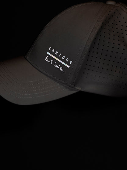 White cap with 'Castore' and 'Paul Smith' branding on a black background