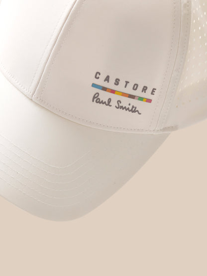 White cap with 'Castore Paul Smith' logo on a beige background