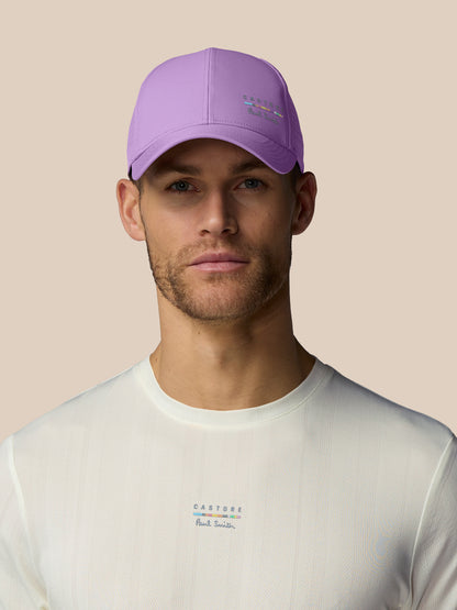 Man wearing a purple cap and white shirt with brand logos on a beige background