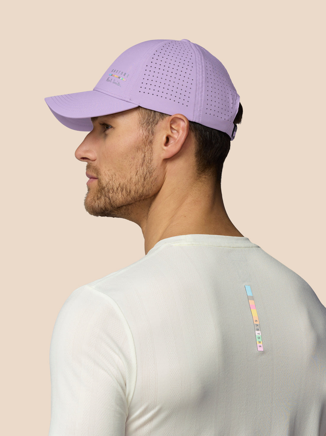 Man wearing a purple cap and white shirt with colorful design on beige background