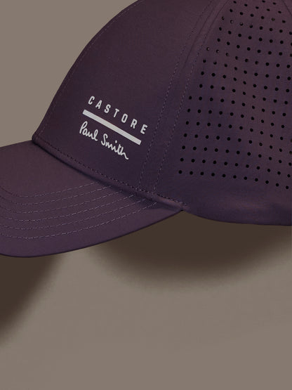 Mauve cap with 'Castore' and 'Paul Smith' logos on a gray background