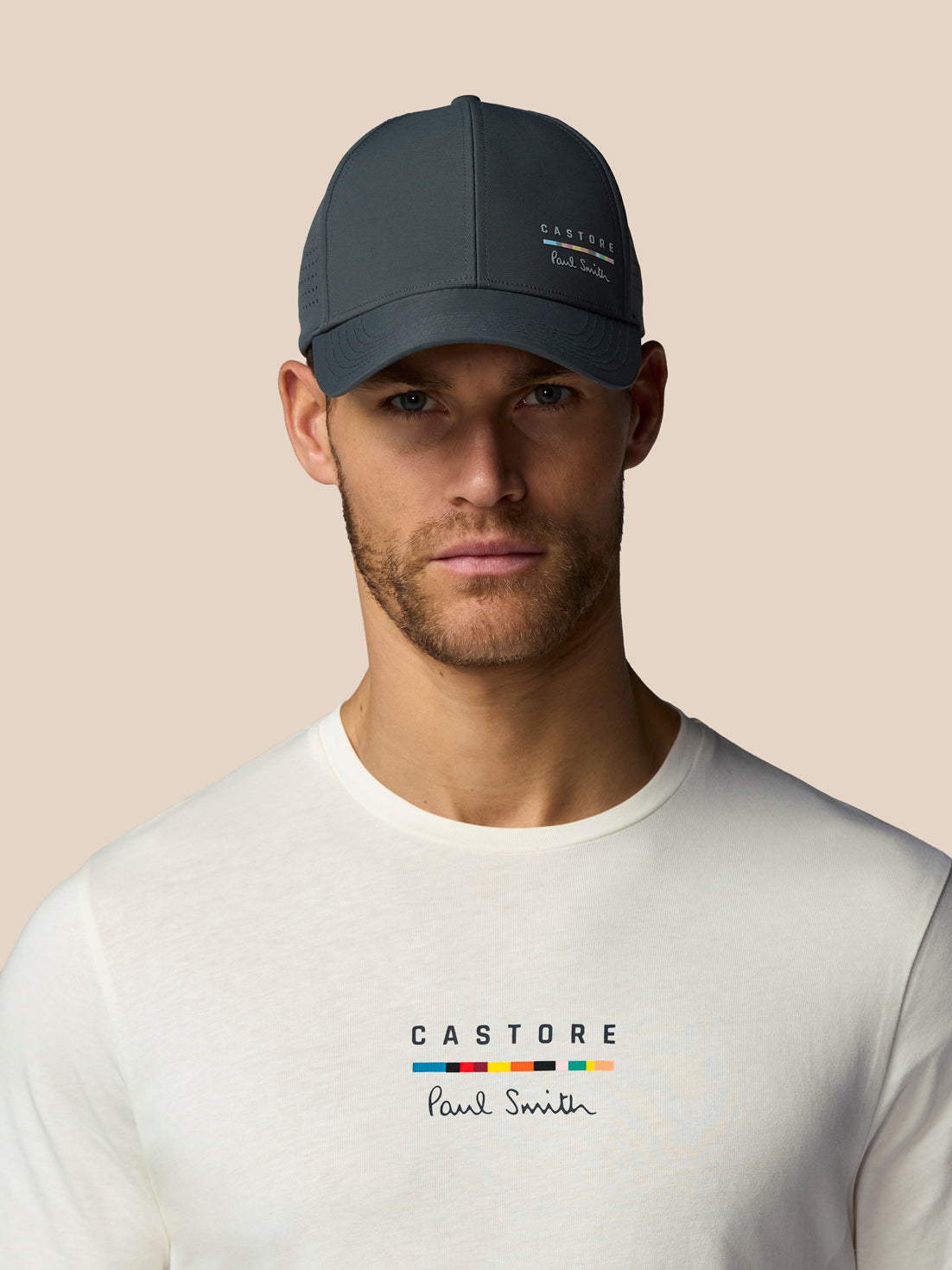 Man wearing a dark gray cap with 'Castore' branding on a beige background