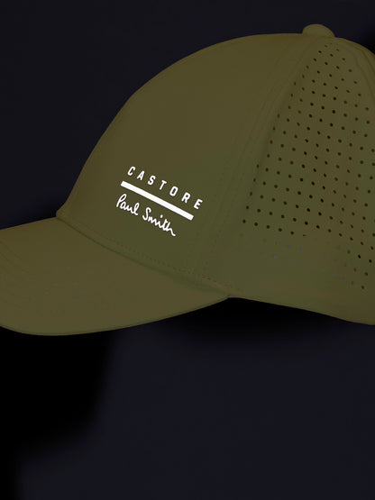 Green cap with 'Castore' and 'Paul Smith' logos on a black background