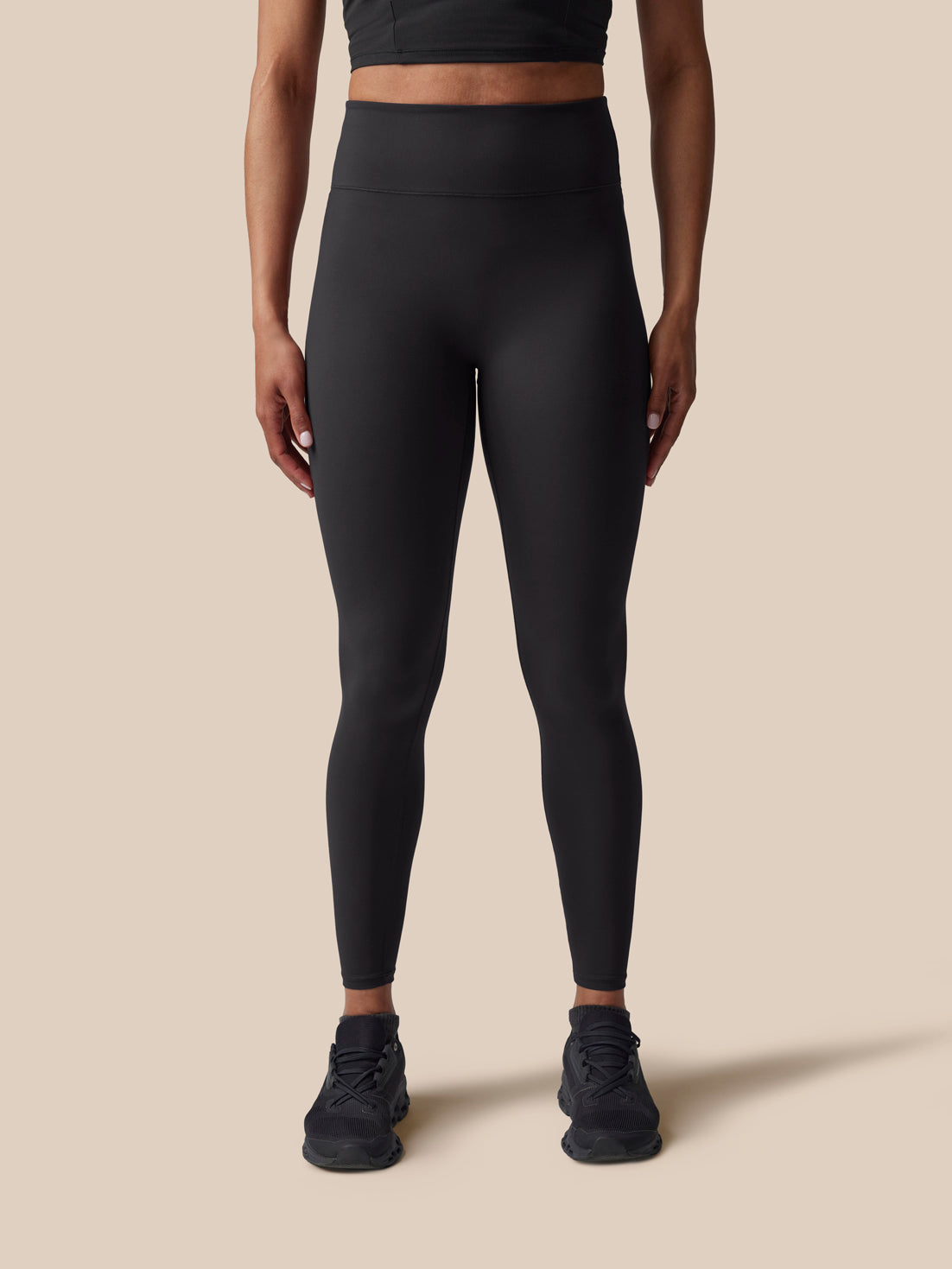 Person wearing black leggings on a beige background