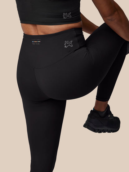 Person wearing black athletic leggings with a beige background