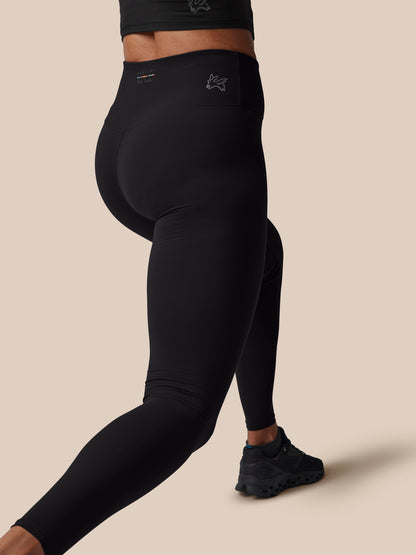 Person wearing black leggings on a beige background