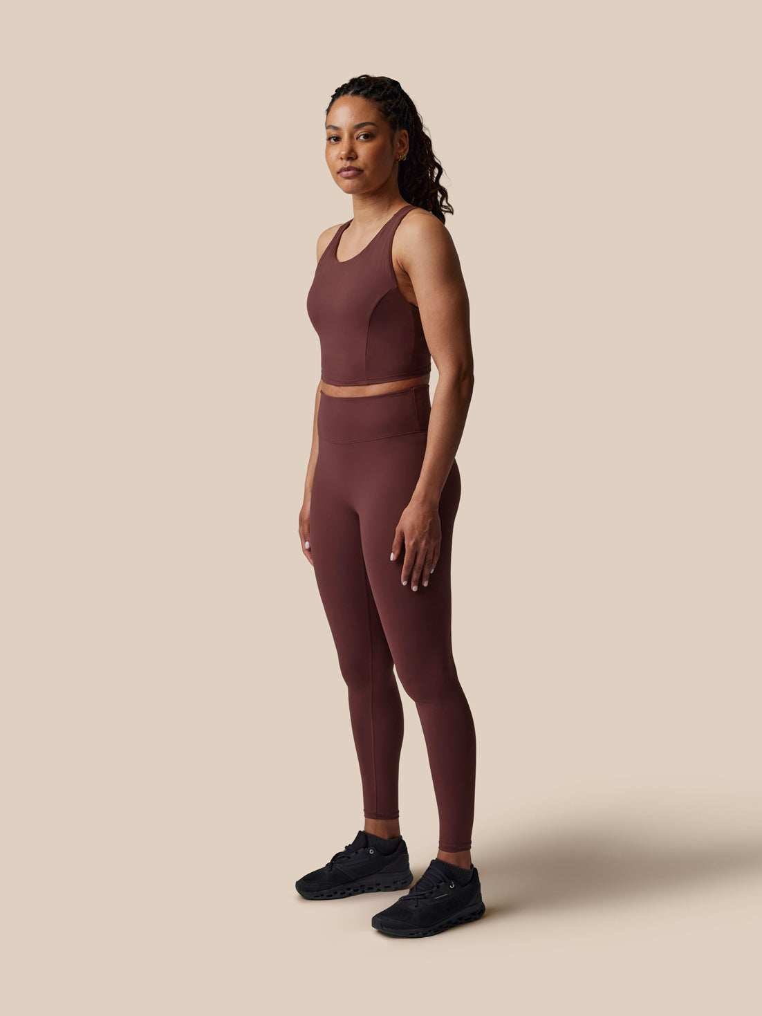 Woman wearing a brown athletic outfit on a beige background