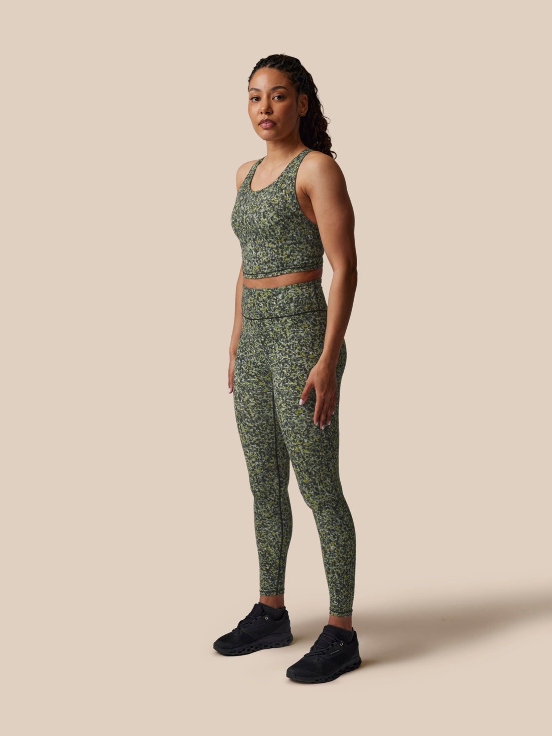 Woman wearing a green patterned athletic outfit on a beige background