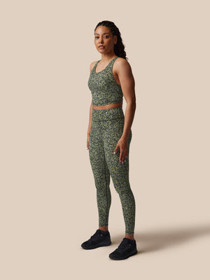 Woman wearing a green patterned athletic outfit on a beige background